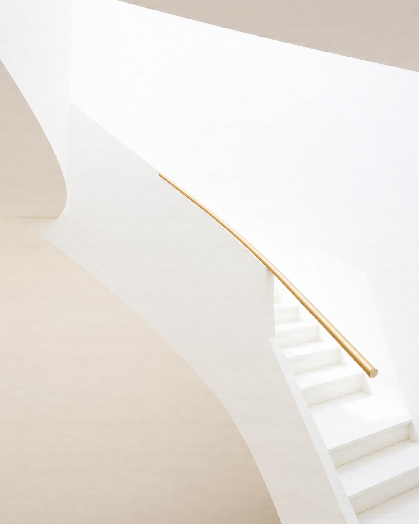 White stair with a slender brushed gold handrail